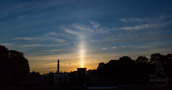 A light pillar behind the silhouette of Vigeland Park | LotsaSmiles Photography